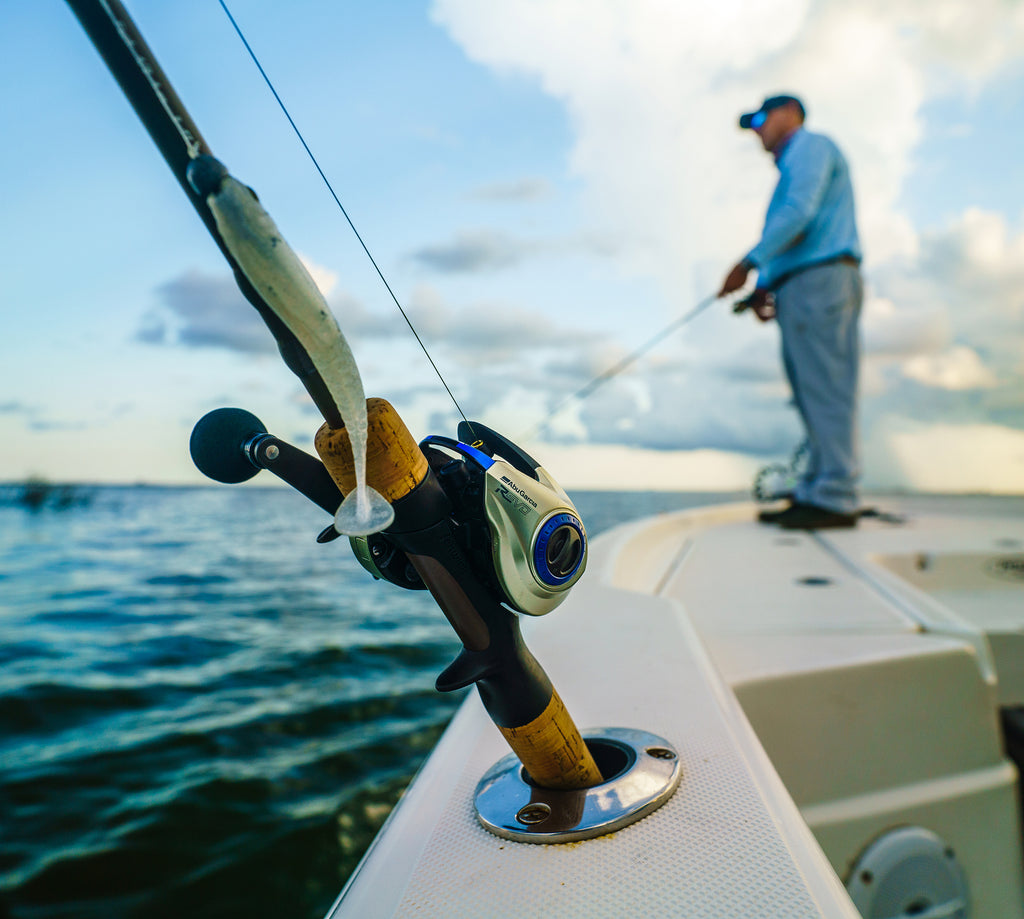 Fishing rod with reel on a boat, person fishing in the background